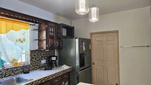 A kitchen with a refrigerator, a coffee maker, and a sink.