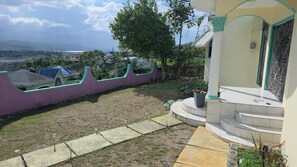 A residential area with a house featuring a small front yard, a staircase leading to the entrance, and a view of the surrounding neighborhood. - Relax & Unwind in Our Tranquil Space at Jamaica b&b rentals (Montego Bay)