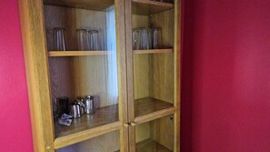 A wooden cabinet with glass-fronted shelves, some containing metal containers.
