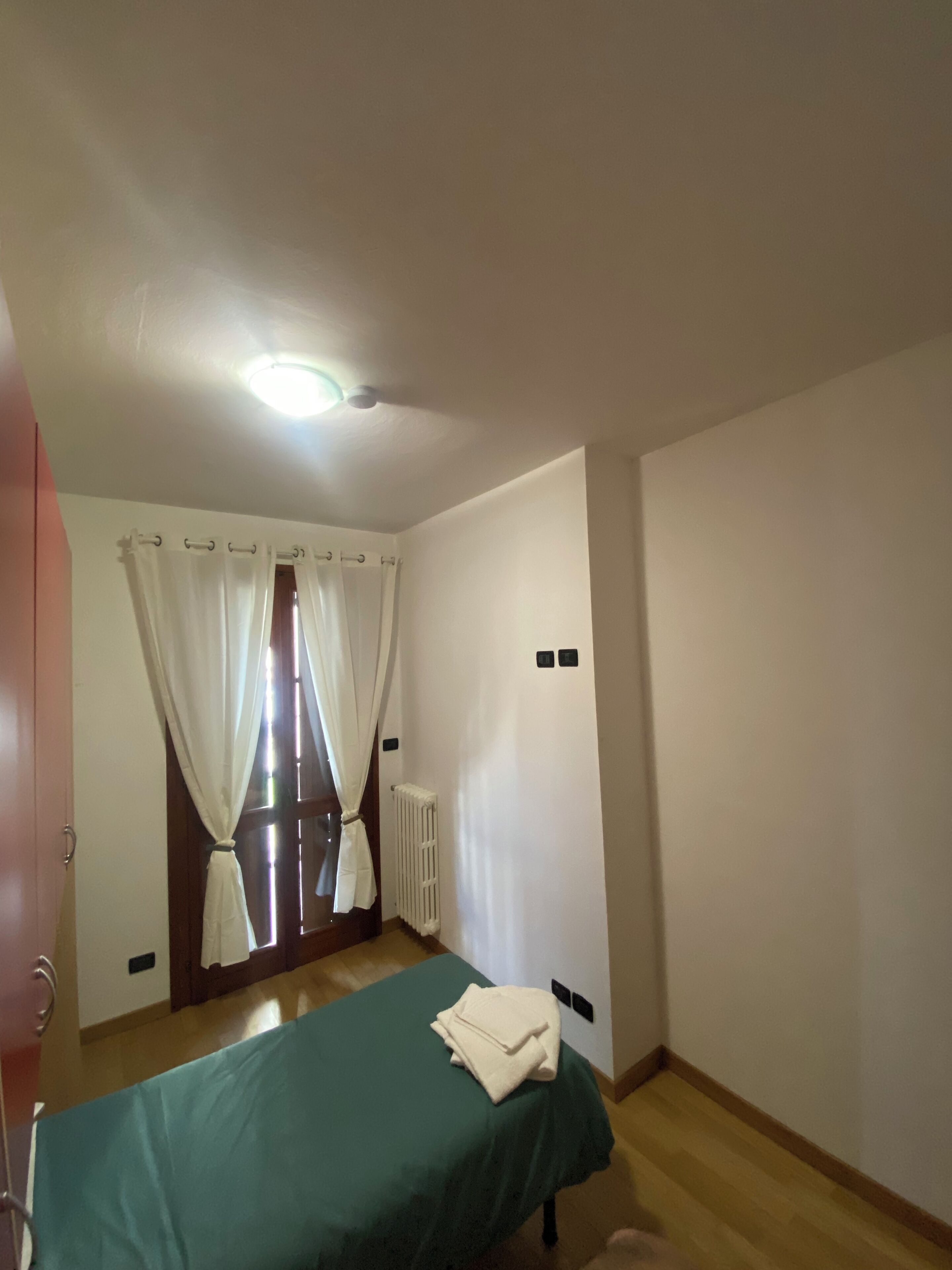 Ein Schlafzimmer mit einem Bett, einem Heizkörper und einem Fenster mit Vorhängen.