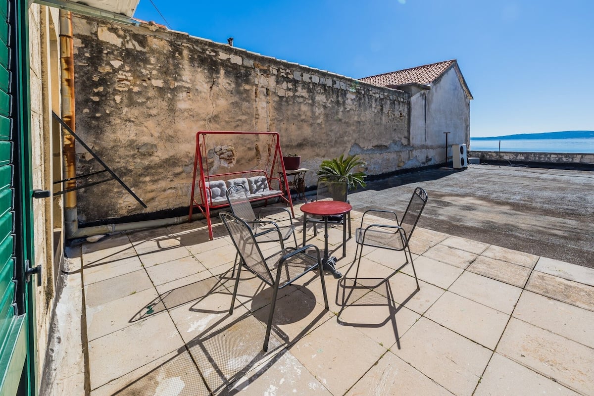 Un patio con mobiliario exterior, una hamaca y vista al mar.