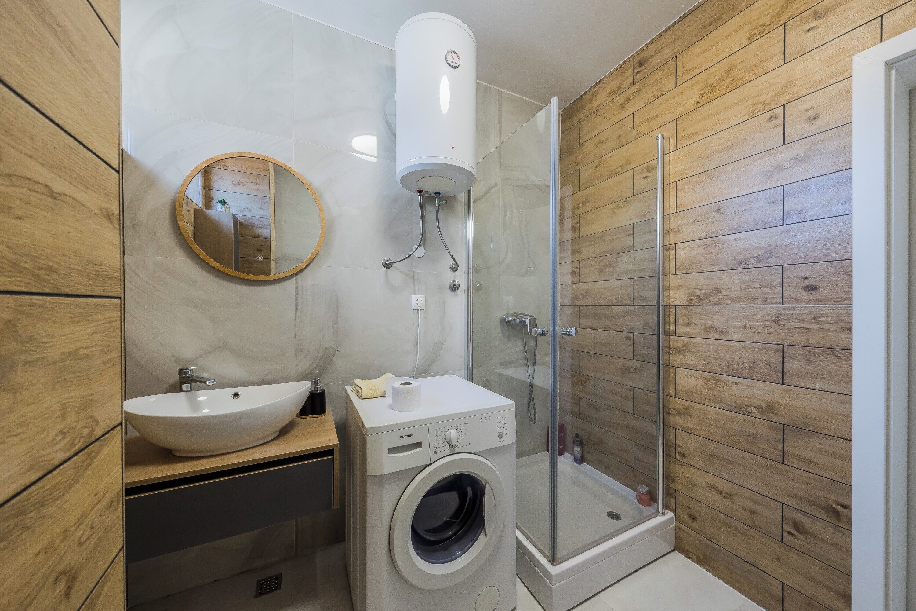 A modern bathroom with a sink, mirror, toilet, and a glass-enclosed shower.