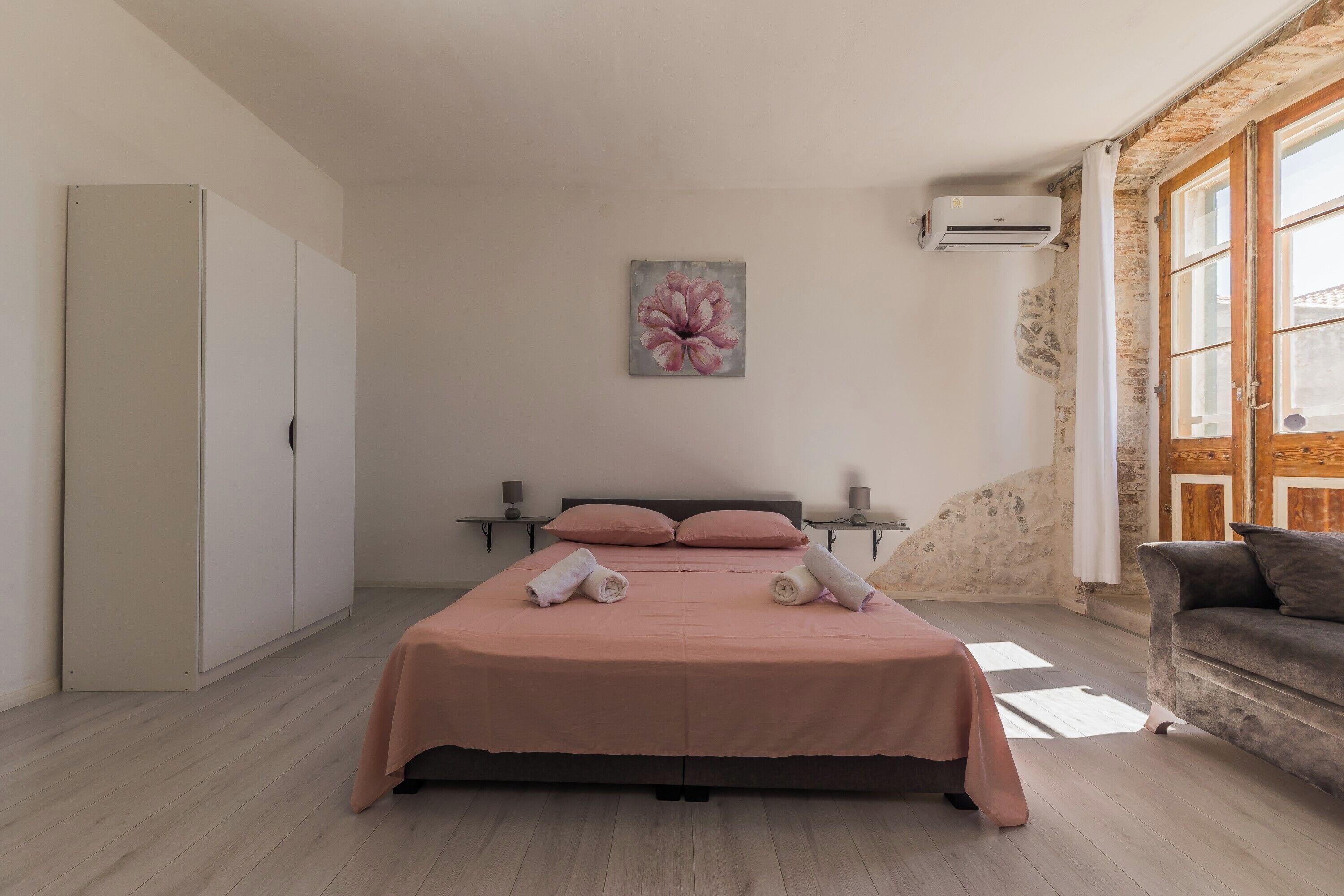 A bedroom with a bed, a nightstand, a chair, and a painting on the wall.