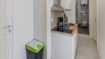 A compact kitchen with a coffee maker, a trash bin, and a sink.