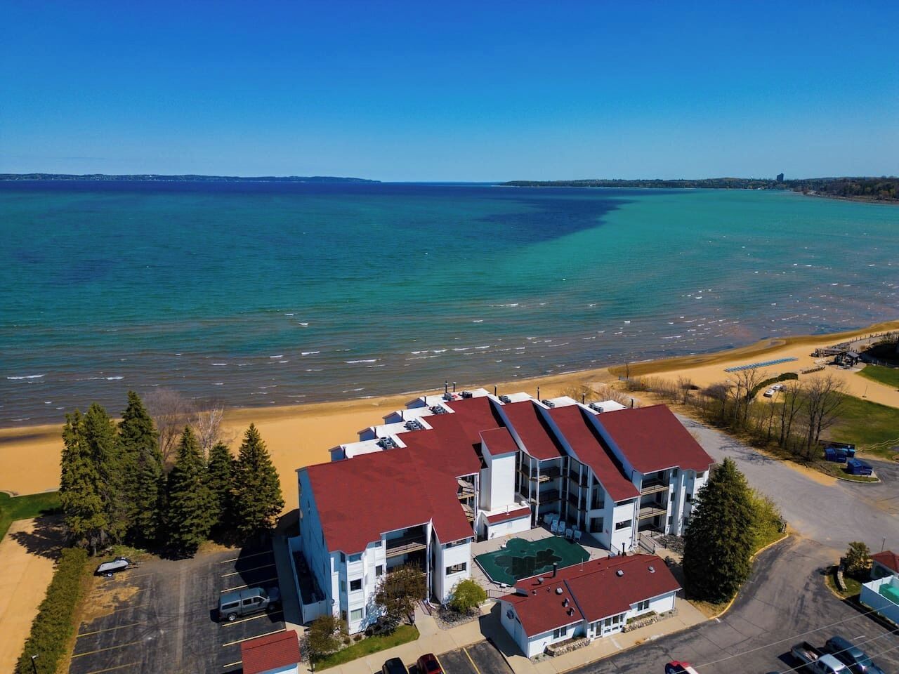 Ein mehrstöckiges Hotel mit rotem Dach in Strandnähe und freiem Blick auf den Ozean.