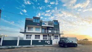 Un immeuble résidentiel à plusieurs étages, doté de balcons et d’une entrée sécurisée par un portail.