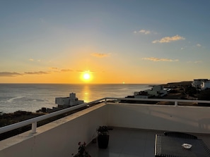 Un balcon avec vue sur la mer et sur le coucher du soleil.