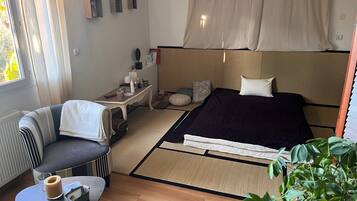 Une chambre d’hôtel compacte comprenant un lit, un petit coin salon, une table de chevet avec des articles de toilette et une vue sur l’extérieur.