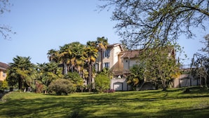 A large, two-story house with a well-maintained lawn and palm trees. - Maison Tournesol Pau Jurançon Gan (Gan)