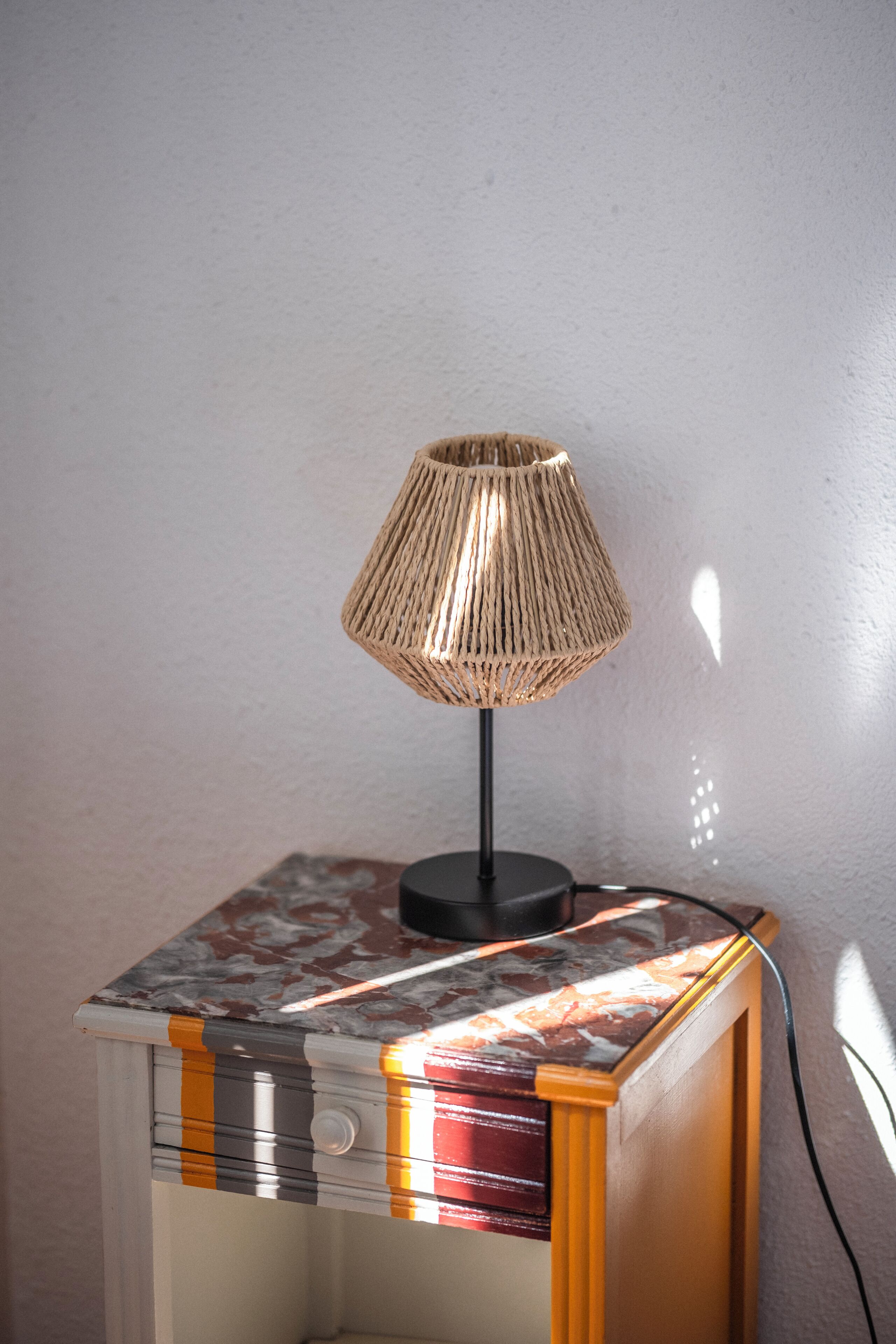 A lamp on a bedside table with a marble top.