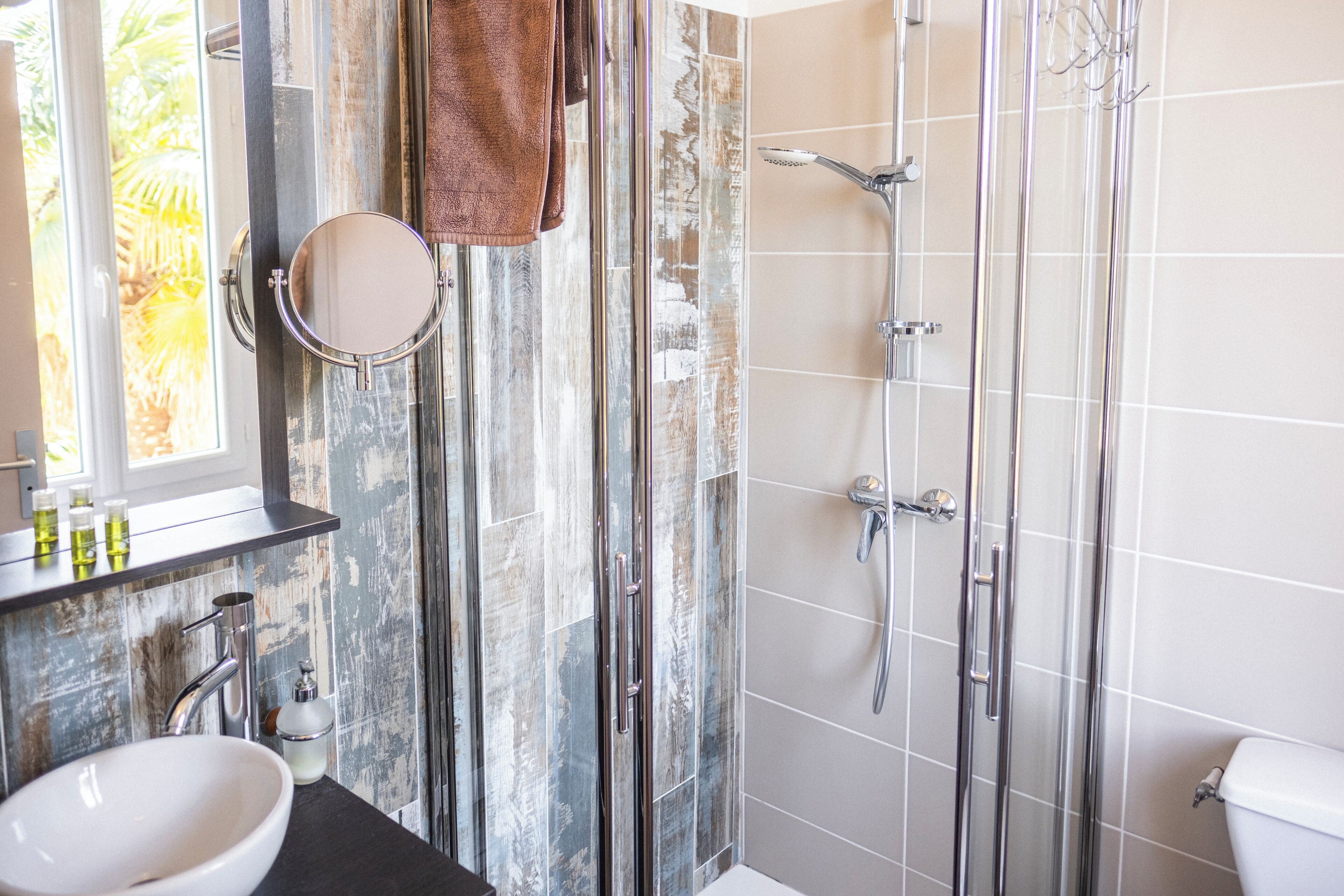 A bathroom with a glass shower enclosure, a white sink, and a mirror.