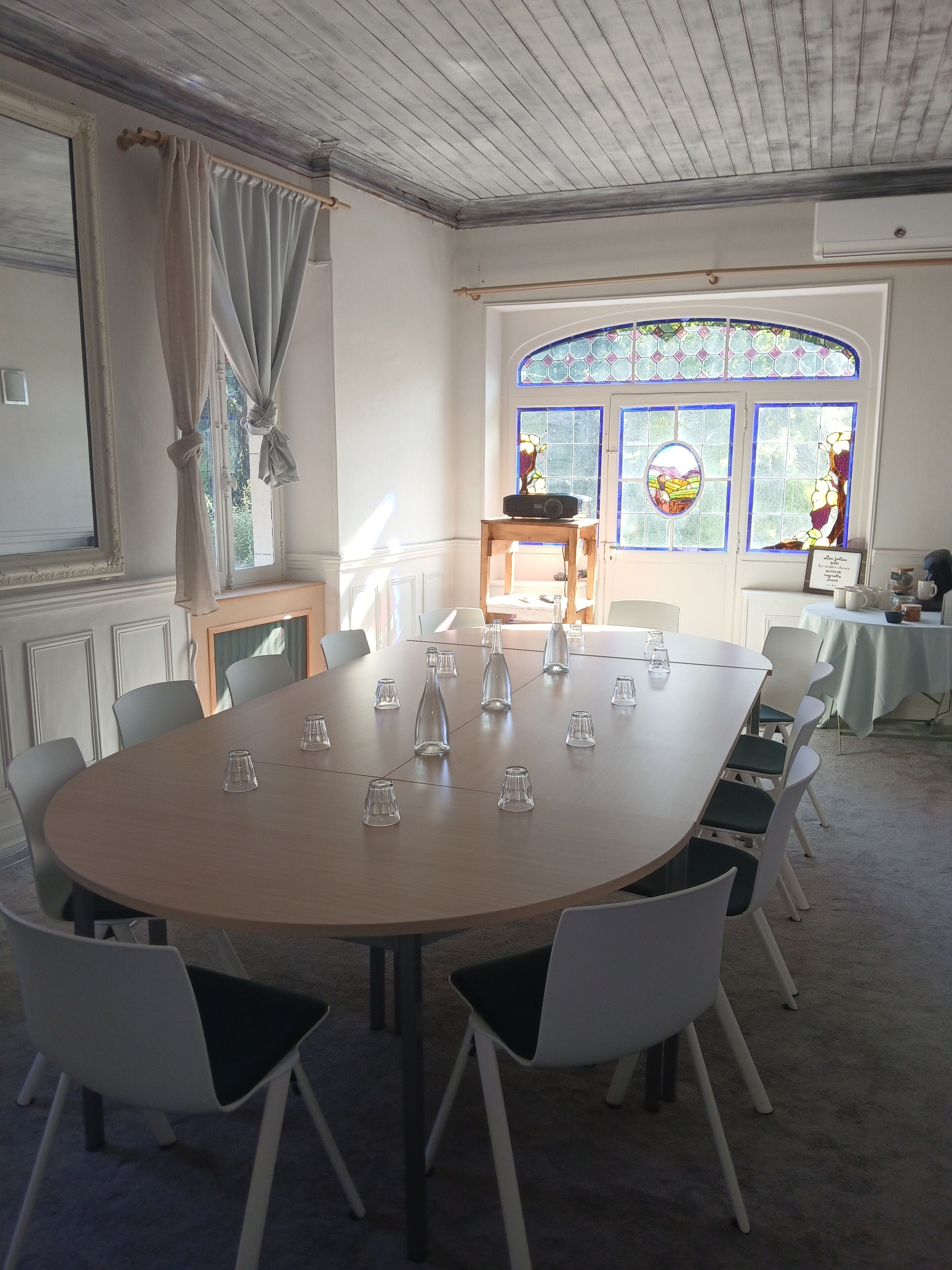 A conference room with a round table, white chairs, and a wooden table with a radio.