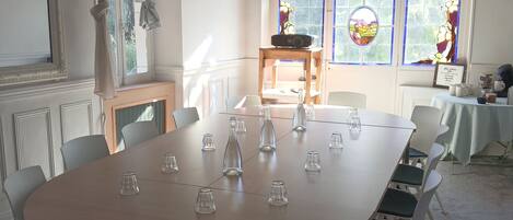 A conference room with a round table, white chairs, and a wooden table with a radio.
