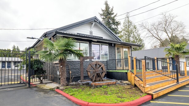 A building with a garage door, a wooden ramp, and a palm tree.