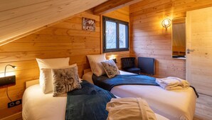 Une chambre confortable en bois, avec deux lits, une télévision et un miroir.