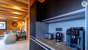 Une cuisine moderne équipée d’une machine à café intégrée, d’un grille-pain et d’une bouilloire, le tout posé sur un plan de travail en bois.