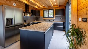 Une cuisine moderne dotée d’un îlot central, d’appareils électroménagers en acier inoxydable et de panneaux muraux en bois.