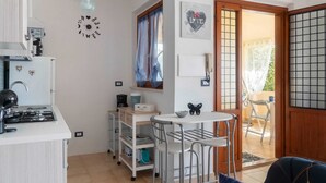 A compact kitchen with a gas stove, a coffee machine, and a small dining area with a table and chairs.