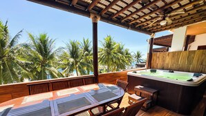 A wooden deck with a hot tub, a table, and chairs, overlooking palm trees and a clear sky. - Villas Le Suisse Monterrico (Taxisco)