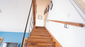 Una escalera de madera con barandilla, un televisor montado en la pared y cuadros enmarcados.
