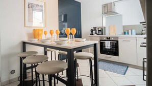 Cocina moderna con comedor, que incluye una mesa negra, cuatro taburetes altos y una cafetera.