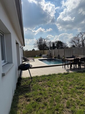 Un pati d'habitatge amb piscina, barbacoa i mobiliari exterior.