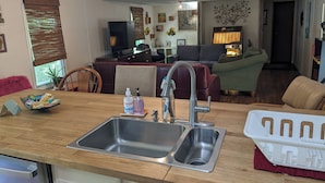 Una cocina con un lavamanos doble, un refrigerador y un comedor con mesa y sillas.