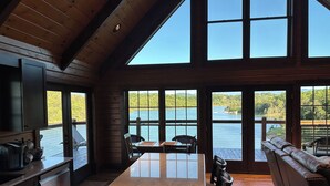 A spacious kitchen with a large island, wooden ceiling, and large windows overlooking a lake. - Lakefront Cabin 3 bed, 3 1/2 bath with Private Dock (Sevierville)