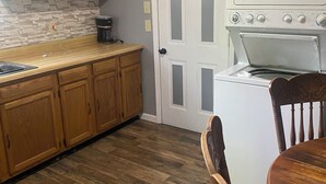 Une cuisine avec des meubles de rangement en bois, une cuisinière blanche et une table à manger avec des chaises.