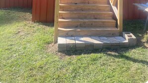 Une maison de plain-pied avec un porche à l’avant et un escalier en bois menant à la porte.