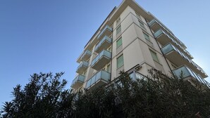Un edificio a più piani con balconi, immerso nel verde.