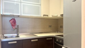 Una cucina con mobili scuri, un lavello in acciaio inossidabile e un frigorifero bianco.