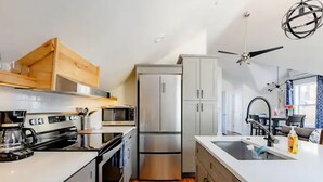 Eine moderne Küche mit Einbauofen, Edelstahlkühlschrank und weißen Schränken.