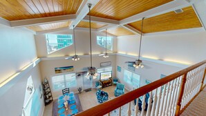 A spacious loft with high ceilings, multiple windows, and a dining area with a wooden table and blue chairs. - Beautiful Home in Gulf Shores With Private Pool, Sleeps 12 (Gulf Shores)