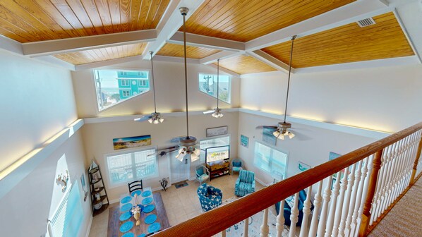 A spacious loft with high ceilings, multiple windows, and a dining area with a wooden table and blue chairs.
