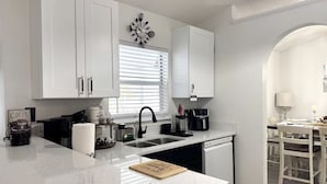 A modern kitchen with white cabinetry, a black faucet, and a coffee machine. - Charming 3-bedroom house with Lake view, in fantastic Kissimmee (Kissimmee)