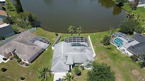 An aerial view of a residential area with a house featuring a large roof, a swimming pool, and a pond. - Charming 3-bedroom house with Lake view, in fantastic Kissimmee (Kissimmee)