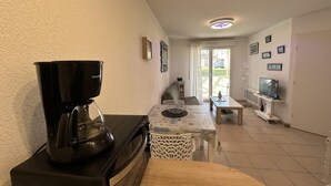 Un espacio habitable compacto con kitchenette, comedor y televisión.