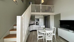 Un espacio habitable compacto con zona de comedor, kitchenette y televisor.