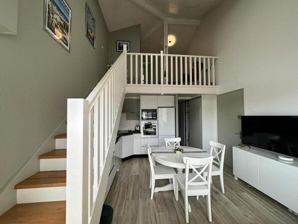 A compact living space with a dining area, kitchenette, and a TV.