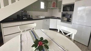 Cocina compacta con muebles blancos, microondas y refrigerador Bosch.
