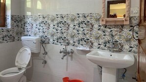 Un baño con inodoro, lavamanos, ducha y un espejo decorativo.