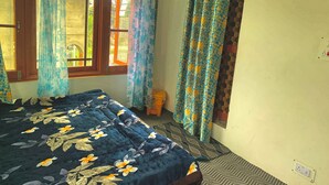 Un dormitorio con cama, cortinas, una ventana y un interruptor de luz en la pared.