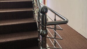 Una escalera con barandilla de metal y peldaños alfombrados.