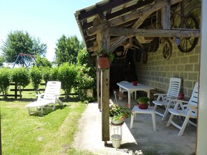 Relax in a serene outdoor space surrounded by lush greenery and a charming pergola.