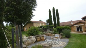 A patio area with stone seating and a small table, surrounded by a gravel path and greenery. - Gascon du Saby - HONTANX (HONTANX)