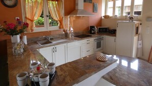 A kitchen with white cabinets, a granite countertop, a sink, a stove, a microwave, and a refrigerator. - Gascon du Saby - HONTANX (HONTANX)