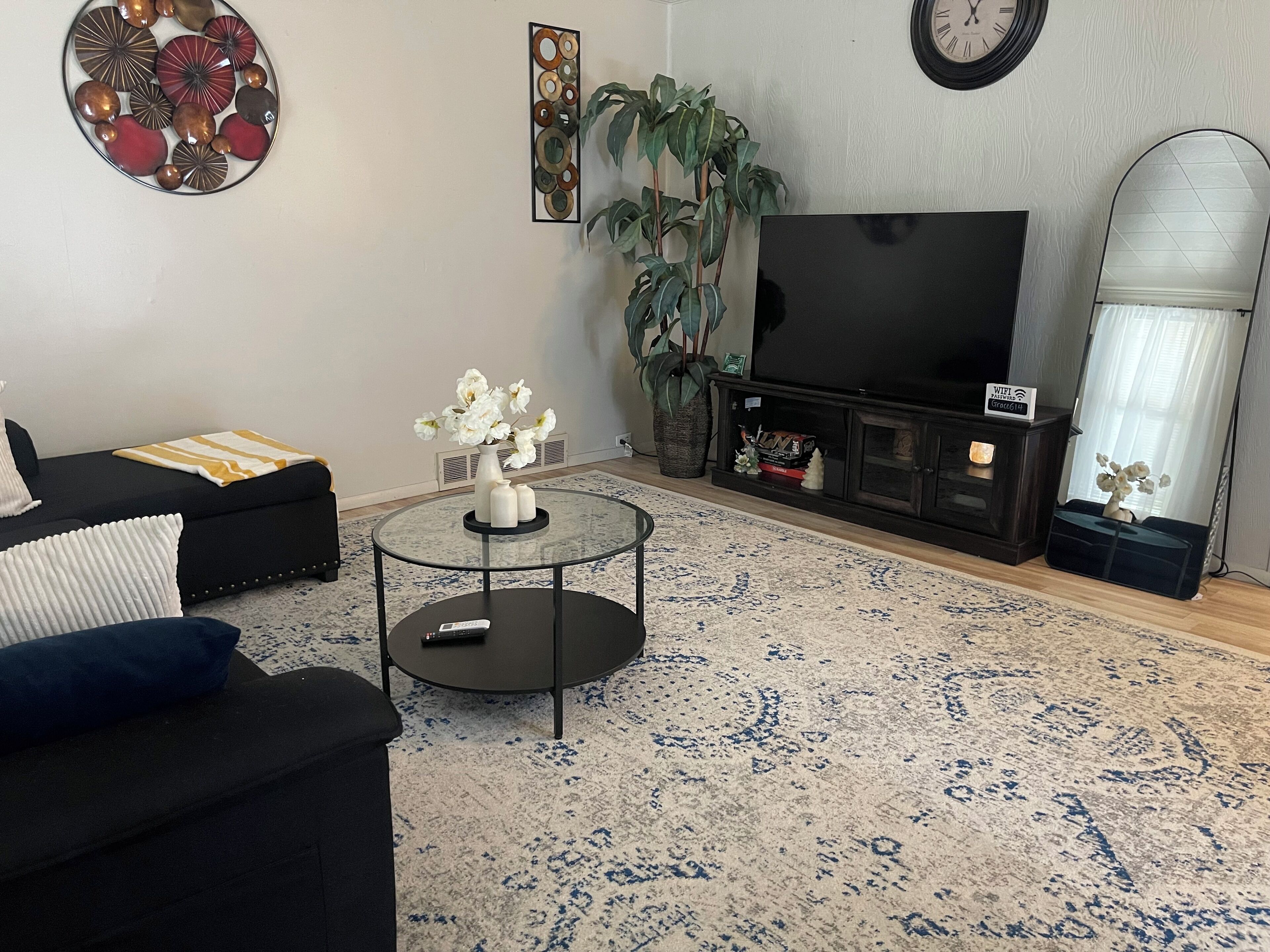 Un salon avec un canapé, une table basse, un téléviseur et un grand miroir.