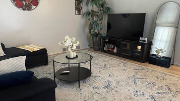 Un salon avec un canapé, une table basse, un téléviseur et un grand miroir.
