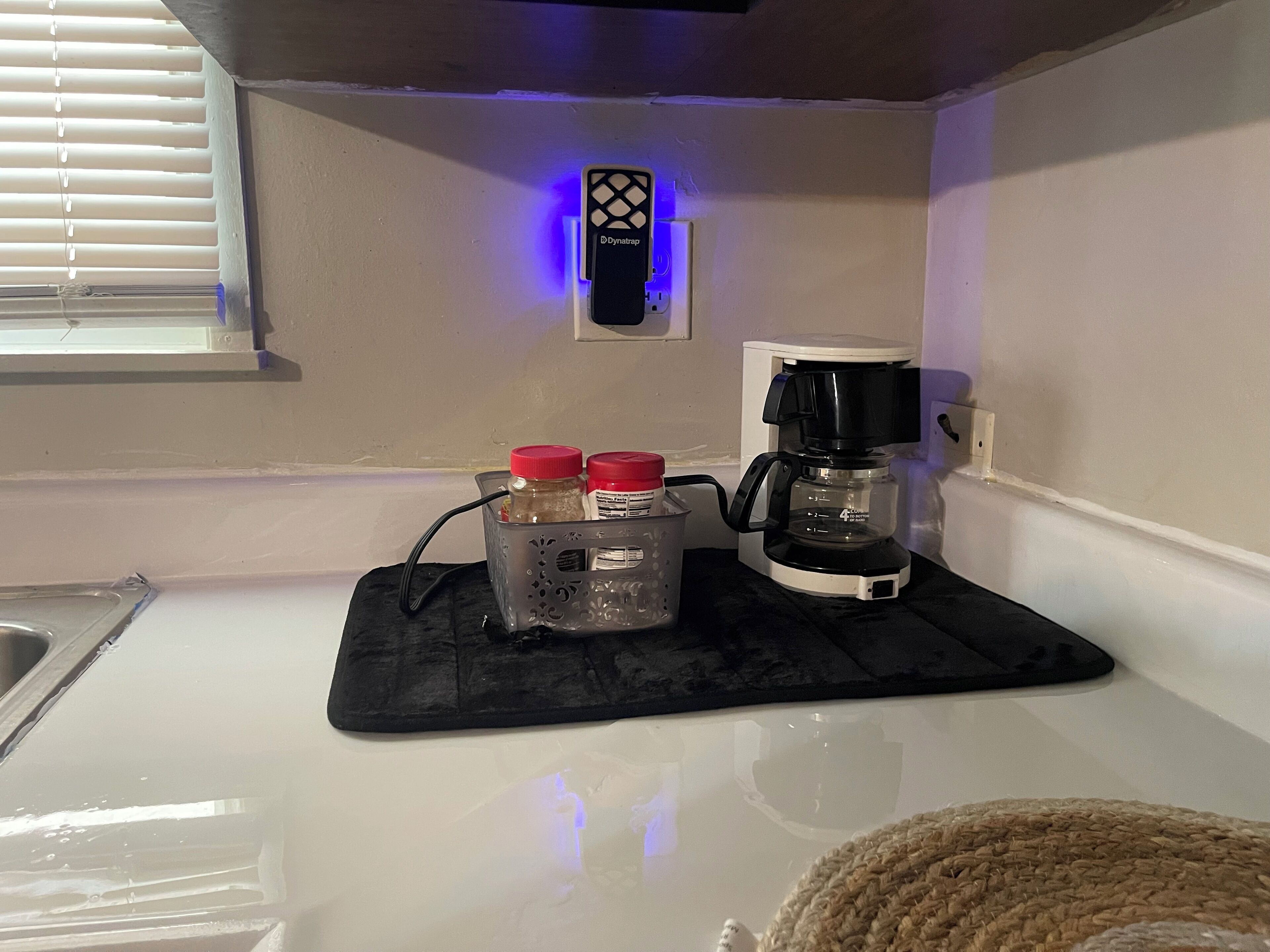 Eine Küchenarbeitsplatte mit einer Kaffeemaschine, einer schwarzen Matte und zwei Gewürzbehältern.